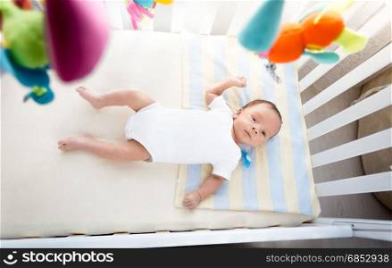 Image from high point of view of little baby lying in white cradle at sunny day