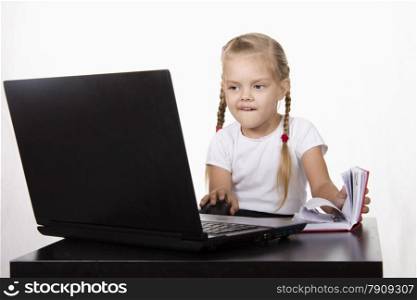 Image of a business girl. girl sitting at table. On table is a laptop, girl it works. girl joyfully looking into laptop other hand opens Notepad