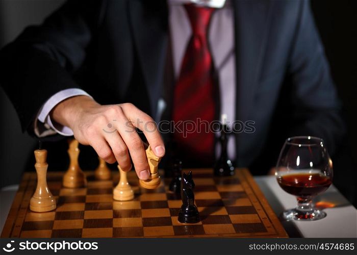 Image of a businessman in dark suit playing chess