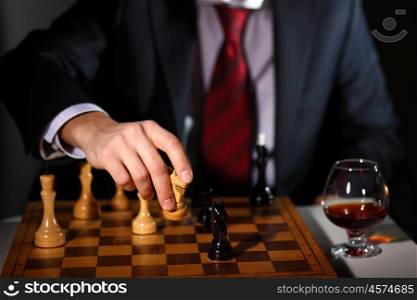Image of a businessman in dark suit playing chess
