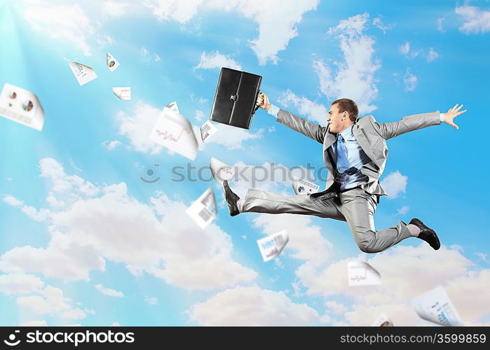 Image of a businessman jumping high against blue sky background