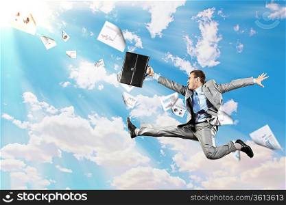 Image of a businessman jumping high against blue sky background