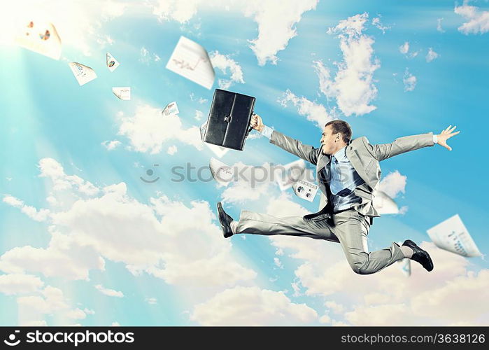 Image of a businessman jumping high against blue sky background