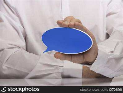 Image of a man hand holding empty blue speech balloon, white shirt and reflexion. . Communication