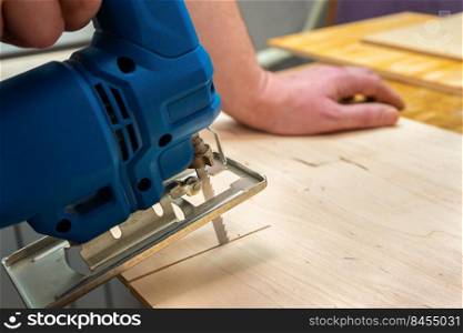 Image of a man hand using electric jigsaw. close up process of cutting wooden board.. Image of a man hand using electric jigsaw