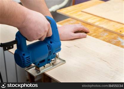 Image of a man hand using electric jigsaw. close up process of cutting wooden board.. Image of a man hand using electric jigsaw