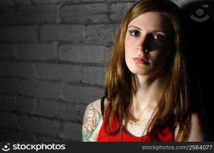Image of a serious girl with upper arm tattoo. Harsh lighting for more dramatic effect.