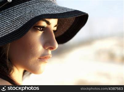 Image of attractive arabic female wearing black beach hat, closeup portrait of stylish elegant woman, beautiful girl isolated on blur background, side view of luxury glamorous young lady