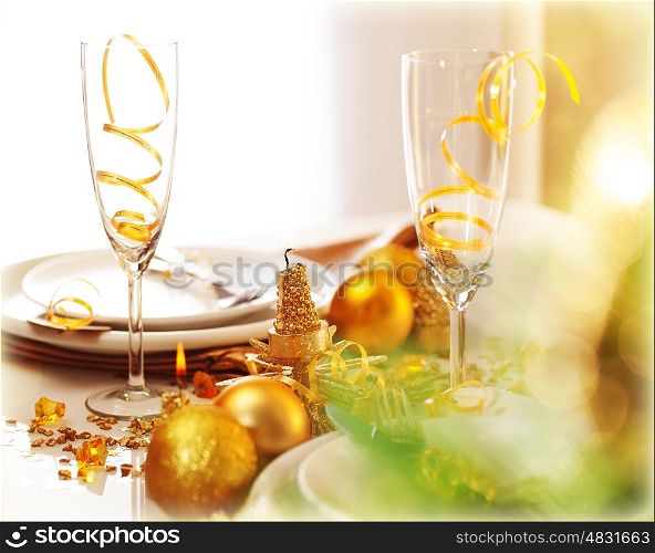 Image of beautiful decorated New Year table setting, romantic holiday dinner in restaurant, golden Christmas decorations, white plates served with silver cutlery and glasses for wine, fir twig&#xA;