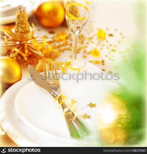 Image of beautiful decorated New Year table setting, romantic holiday dinner in restaurant, golden Christmas decorations, white plates served with silver cutlery and glasses for wine, fir twig