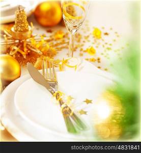 Image of beautiful decorated New Year table setting, romantic holiday dinner in restaurant, golden Christmas decorations, white plates served with silver cutlery and glasses for wine, fir twig