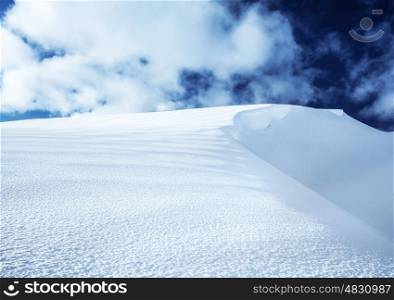 Image of beautiful snowy hill and dark blue cloudy sky, top of the mountain covered with white snow, peaceful winter landscape, wintertime seasonal weather, Christmastime vacation