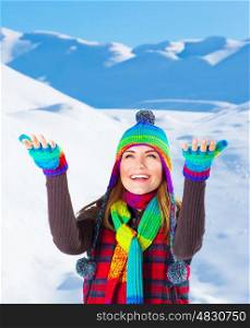Image of beautiful woman playing outdoors in winter, cute teenager girl with raised up hands having fun in snowy mountains, wintertime fashion, warm colorful stylish clothes, holidays and vacation