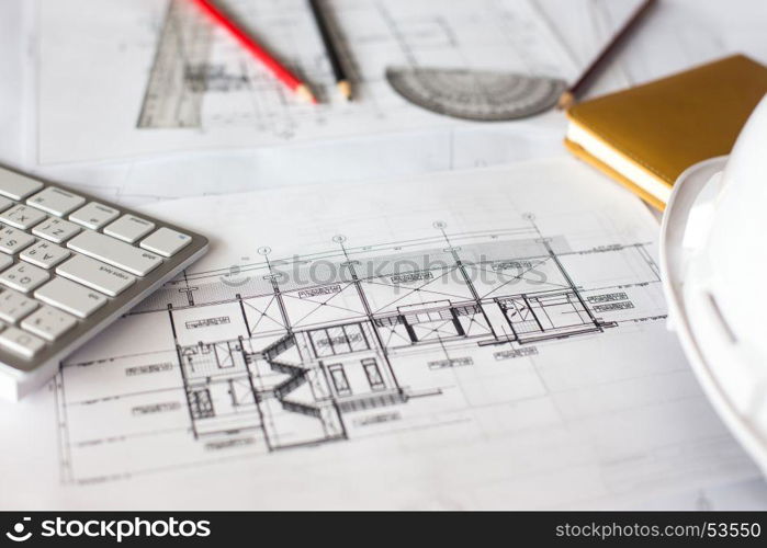 Image of blueprints with level pencil and hard hat on table.