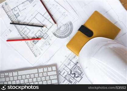 Image of blueprints with level pencil and hard hat on table.