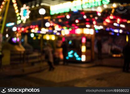 Image of blur street with festive lights and carousel in night time. Blur bokeh light defocused background