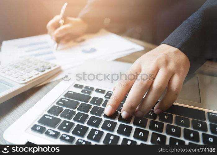 image of bookkeeper / financial inspector calculating on investment data with documents and laptop in dark office room