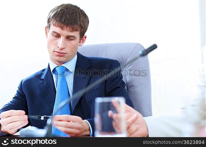 Image of bored businessman holding pen at meeting