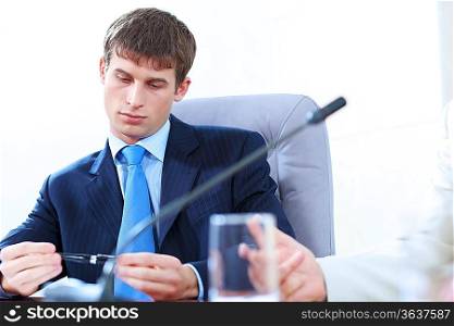 Image of bored businessman holding pen at meeting