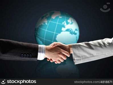 image of business handshake. business handshake against black background with globe image