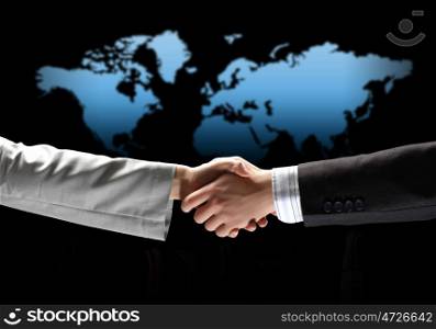 image of business handshake. business handshake against black background with map image
