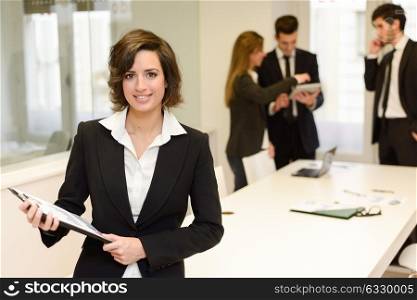 Image of business leader looking at camera in working environment. Woman with folder in her hands
