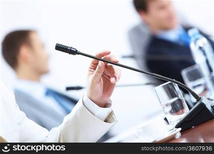 Image of businessman&acute;s hands holding microphone at conference