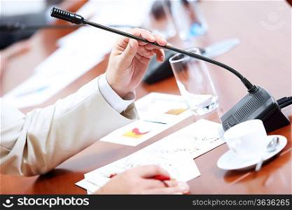 Image of businessman&acute;s hands holding microphone at conference
