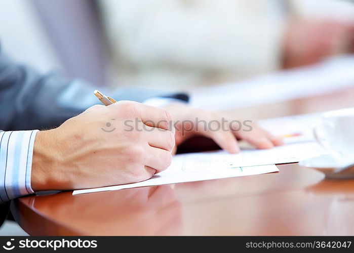 Image of businessman&acute;s hands signing documents at meeting