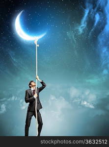 Image of businessman climbing rope attached to moon