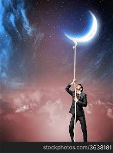 Image of businessman climbing rope attached to moon