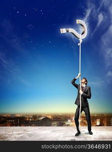 Image of businessman climbing rope attached to question sign aloft against city background