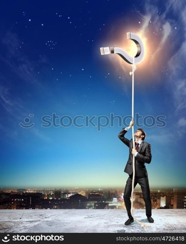 Image of businessman climbing rope. Image of businessman climbing rope attached to question sign aloft against city background