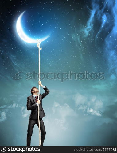 Image of businessman climbing rope. Image of businessman climbing rope attached to moon
