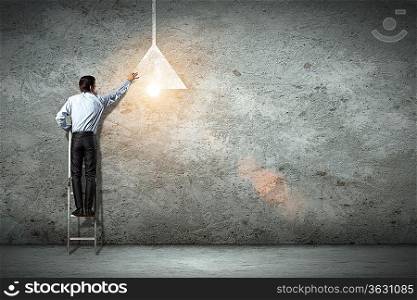 Image of businessman drawing lamp on wall