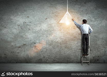 Image of businessman drawing lamp on wall