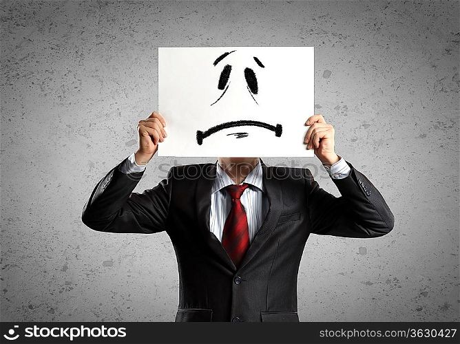 Image of businessman holding drawing of upset face. Conceptual photo