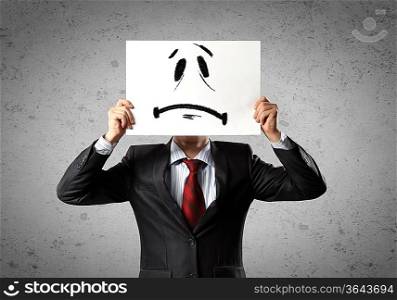 Image of businessman holding drawing of upset face. Conceptual photo