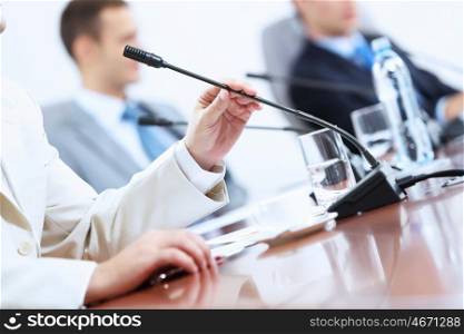 Image of businessman's hands holding microphone at conference