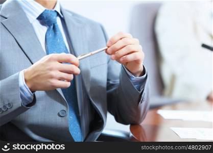 Image of businessman's hands laying on table with pen