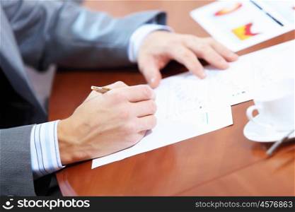Image of businessman's hands signing documents at meeting