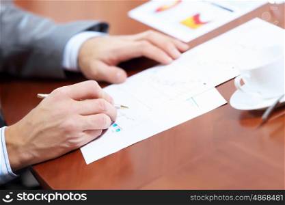 Image of businessman's hands signing documents at meeting