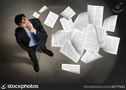 Image of businessman top view. Image of printed materials flying in air top view against businessman background