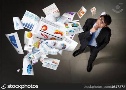 Image of businessman top view. Image of printed materials flying in air top view against businessman background