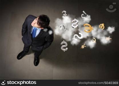 Image of businessman top view. Top view of young businessman making decision currency signs in air