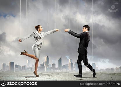 Image of businesspeople hanging on strings like marionettes against city background. Conceptual photography