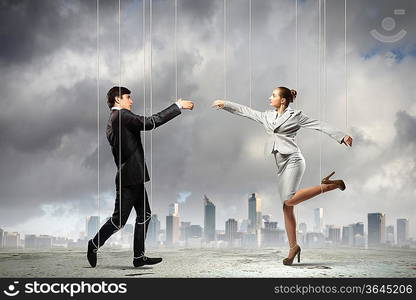 Image of businesspeople hanging on strings like marionettes against city background. Conceptual photography