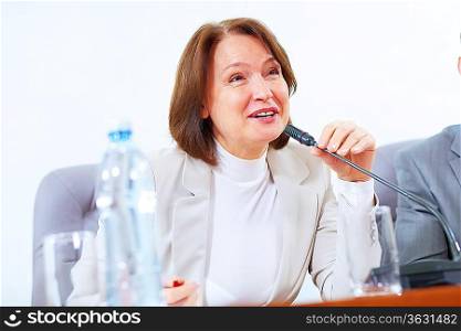 Image of businesswoman at business meeting speakig in microphone