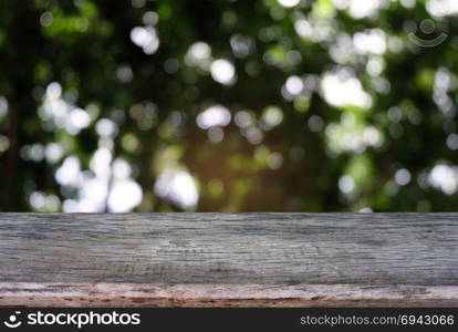 Image of dark wooden table in front of abstract blurred background of outdoor garden lights. can be used for display or montage your products.Mock up for display of product.