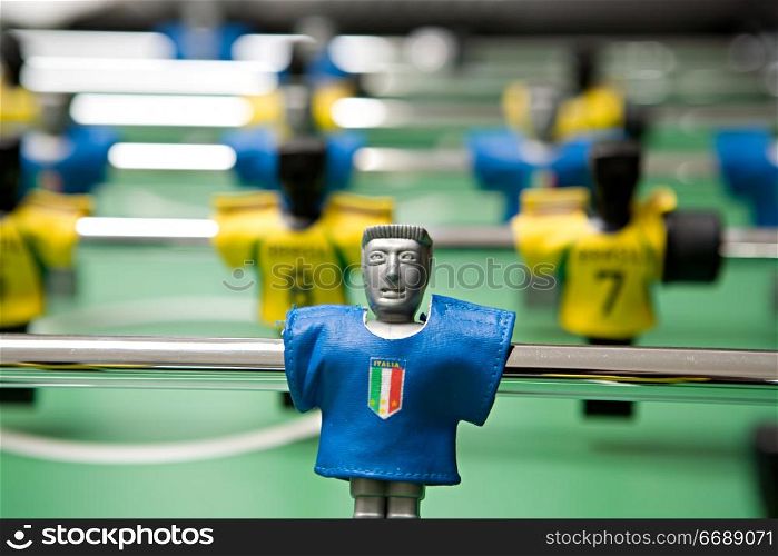 Image of desktop football with plastic players in the dark blue and yellow form close up on a green background